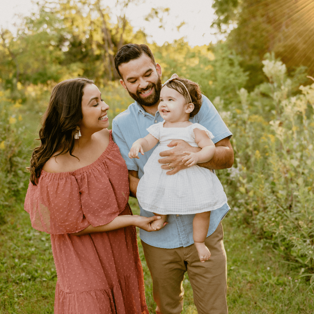 A bright photo of a family of 3 in a green field