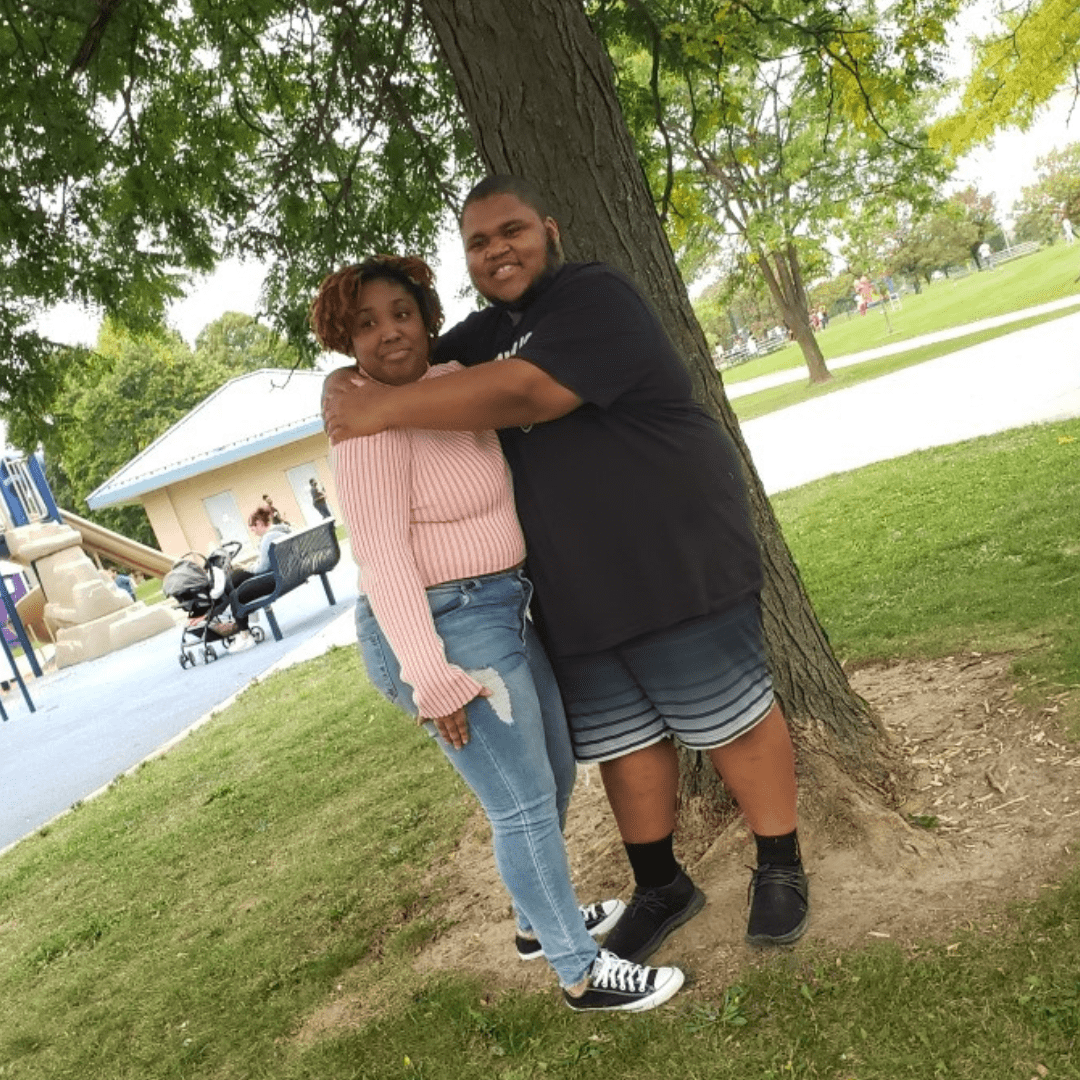 A young Black couple poses together at a park